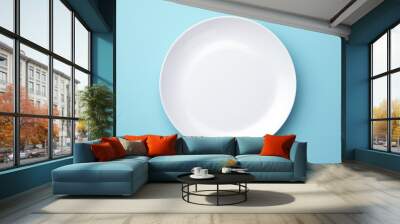 A simple white plate on a blue surface. Perfect for food or kitchen-related designs Wall mural