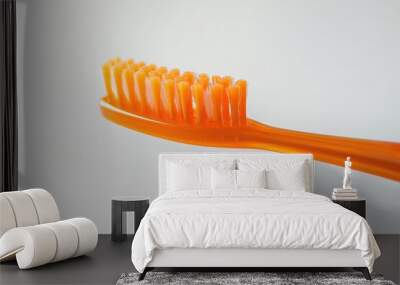 A single orange toothbrush placed on a clean white surface Wall mural