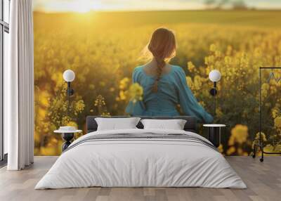 A woman in a blue dress walks through a field of bright yellow flowers Wall mural