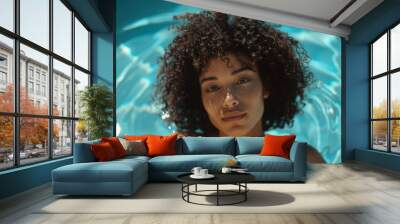 A woman relaxing in an outdoor swimming pool, with curly hair and smiling face Wall mural