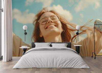 A woman with glasses smiling and raising her arms in joy. Suitable for lifestyle and happiness concepts Wall mural