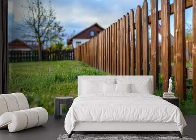 A wooden fence surrounds a lush green grassy yard Wall mural