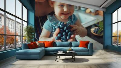 A young girl holds a bunch of fresh blueberries, ideal for food or decoration Wall mural