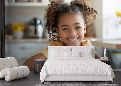 A young girl sits at a table with a bowl of cereal and a spoon, ready for her morning meal Wall mural