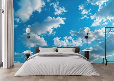 Aerial view of a plane soaring through a bright blue sky with clouds Wall mural