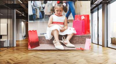 little girl crying in the mall with colored bags Wall mural