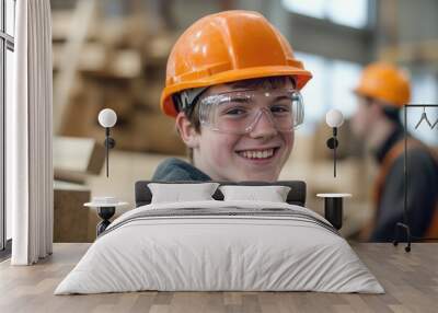 Young man in a hard hat and safety glasses working on construction site. Wall mural