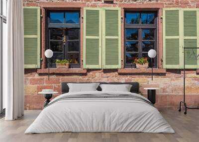 Close-up of a red house facade with two windows with green wooden shutters Wall mural