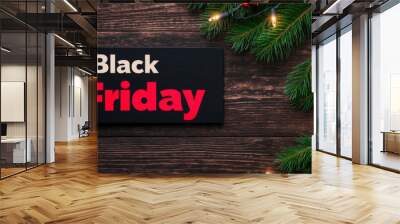 Black Friday in classic red and white on a rustic wood background with holiday greenery and twinkle lights  Wall mural