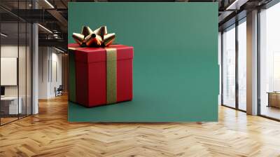 Bright red gift box with a golden bow isolated on a plain green background  Wall mural