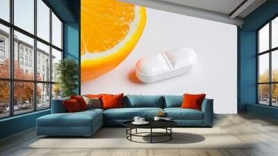 close-up of a vitamin C tablet with a sliced orange, isolated on a white background, bright and fresh  Wall mural