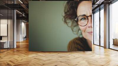 Portrait of a smiling middle-aged woman with curly hair wearing round glasses, with ample copy space on the left, ideal for advertisements or inspirational quotes Wall mural