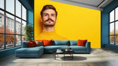 Stylish man with a pencil-thin mustache posing against a bright yellow background with empty space for text  Wall mural