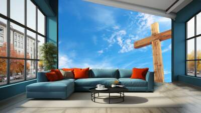 Wooden cross against a vibrant blue sky with fluffy clouds, symbolizing Christian faith and Easter, with copy space for text Wall mural