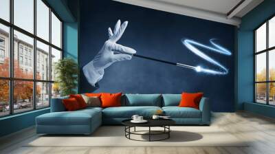 Magician hand holding magic wand on dark background Wall mural