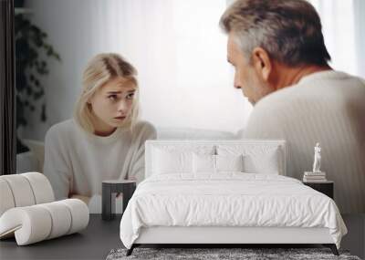 Blonde girl hold hands crossed, sit at sofa and talk with man at home, teen daughter and middle aged father argument, adolescence problems, two generation conflict concept Wall mural