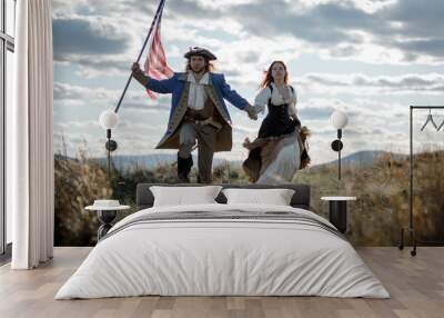 Man in form of officer of War of Independence and girl in historical dress of 18th century. July 4 is US Independence Day. Couple of patriots freedom fighters in outdoor on background cloudy sky Wall mural