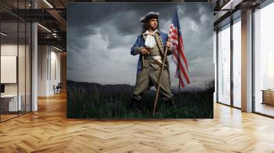 Man in United States War of Independence soldier costume with flag posing in forest. 4 july independence day of USA concept photo composition Wall mural