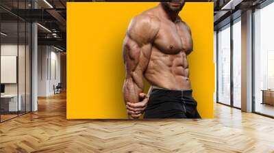 Muscular bodybuilder fitness man with perfect body  shows muscles isolated over yellow background. Workout bodybuilding concept. Wall mural