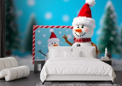 A toy snowman in a Santa hat is on a postcard with a merry Christmas design and a bright blue background scene. Wall mural