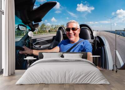 Fisheye view of a handsome middle age man driving a convertible automobile on the highway Wall mural