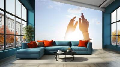 Female lifting hands up to sunset sky Wall mural