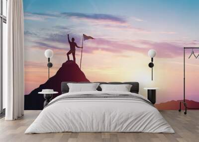 Man with flag celebrates victory on top of a mountain at sunset Wall mural