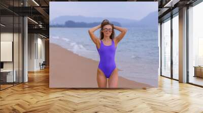 Beautiful slim girl in a blue swimsuit on the ocean. Wall mural