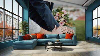 Hands of a bride and groom with wedding rings and a flowers  bouquet Wall mural