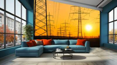 Electricity poles and electric power transmission lines against vibrant orange sky at sunset on a hot day with flickering air. High Voltage towers provide power supply over a long distance. Wall mural