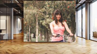 beautiful young girl riding bicycle in the park Wall mural