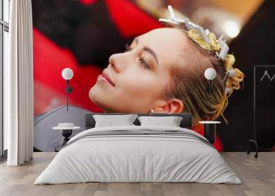 Portrait of beautiful young woman sitting in a hair salon, ready for a new hair style in a blurred background Wall mural