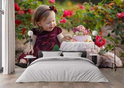 Little girl and decorated party with a cake in the flowers garden Wall mural