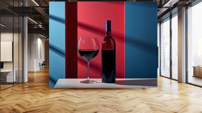 bottle and a glass of red wine are placed on a wooden table against a blue background with gobo shadow effect Wall mural