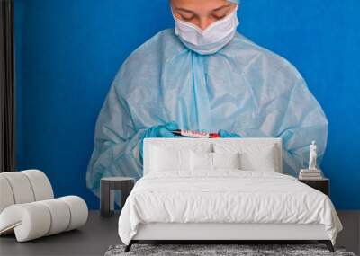 Blood test. A young medical worker holds a blood tube with the inscription covid-19 Wall mural