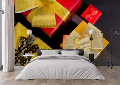 Colorful presents with gold bows on a black background, perfect for Christmas gift-giving themes and holiday celebrations Wall mural