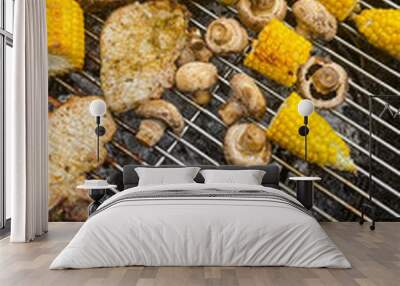 Grilled corn, mushrooms, and pork chops cooking on a barbecue grill during a summer backyard BBQ Wall mural