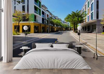 Sunny urban street with modern colorful apartment buildings, empty road with trees, concept of urban development and real estate Wall mural