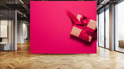 Brown paper gift box with a magenta satin ribbon bow on pink background on the right with copy space. Flat lay Valentines day father mother day and presents concept Wall mural