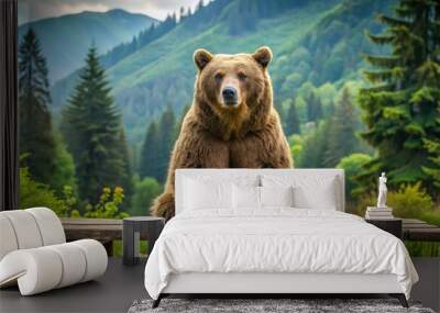 A large, furry brown bear sits calmly on a weathered wooden picnic table amidst a serene forest backdrop, surrounded by lush greenery and rugged terrain. Wall mural