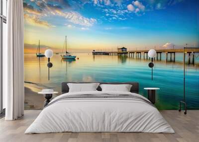 Serene morning scene of calm turquoise waters gently lapping the shore of Biloxi Beach, with a few boats and pier visible in the distance. Wall mural