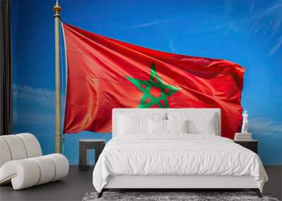 Vibrant red and green Moroccan flag waving against a clear blue sky, with subtle folds and creases, symbolizing national pride and cultural identity. Wall mural