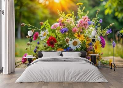 Vibrant wildflowers in a loose bunch rest on a rustic wooden table, set against a lush green natural garden backdrop with soft summer lighting. Wall mural