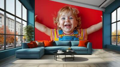 Toddler squealing with unbridled joy, arms flung wide on a vibrant red background. Wall mural