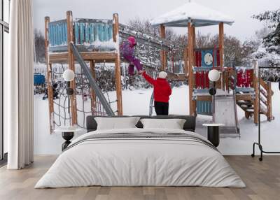 A woman with a child, Caucasian 2 people, walk and play on the playground on a winter day. Wall mural