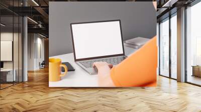 Over shoulder view of cartoon character man working on laptop with mockup blank display at white table. Wall mural