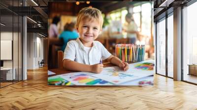 Cute child todler boy draws with colored pencils at the table in the children's room, in kindergarten, in developmental classes, art school. Happy kid doing creativity Wall mural