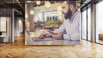 view from the side, a bearded man in a shirt using a laptop sitting at a table in a café, in a man's Wall mural