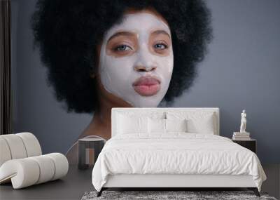 Portrait of gorgeous african girl with a purifying mask winking and flirting on camera. Amazing black female model isolated on dark background. Wall mural