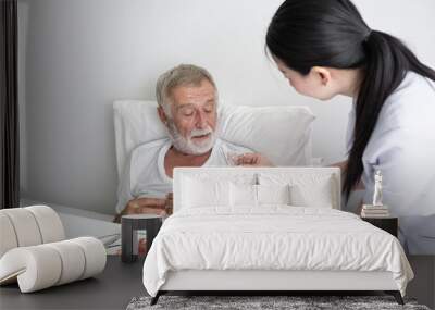 nurse give pill to senior man after breakfast and discussion on bed at nursing home Wall mural